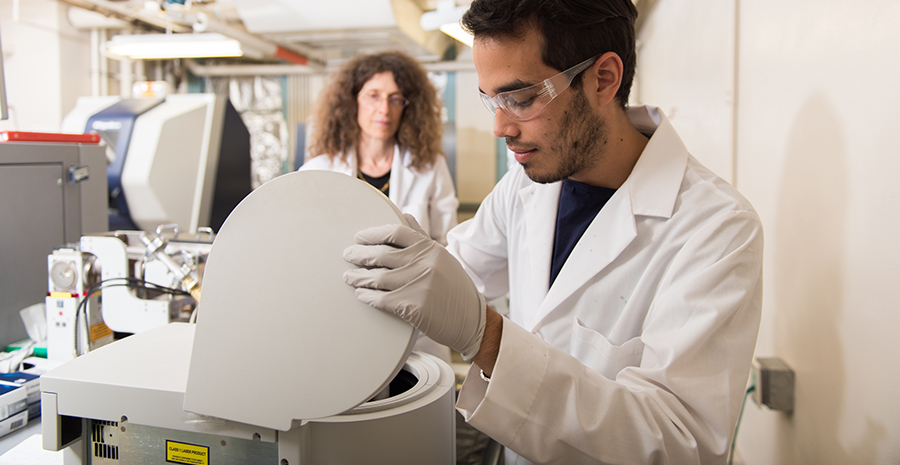 May Nyman watches Ian Colliard working in the lab
